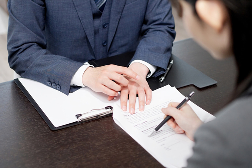 司法書士が依頼者に会社・法人登記の契約書や手続きを説明している様子