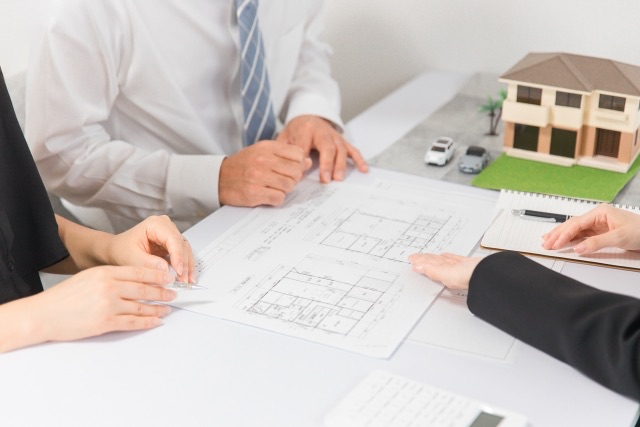 夫婦が司法書士・行政書士・土地家屋調査士に家の間取り図を見ながら相談している様子