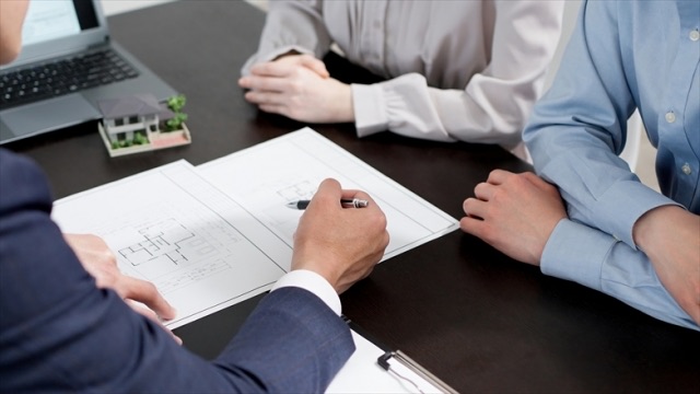 夫婦が司法書士・行政書士・土地家屋調査士から費用や手続きの説明を受けている場面、契約のイメージ